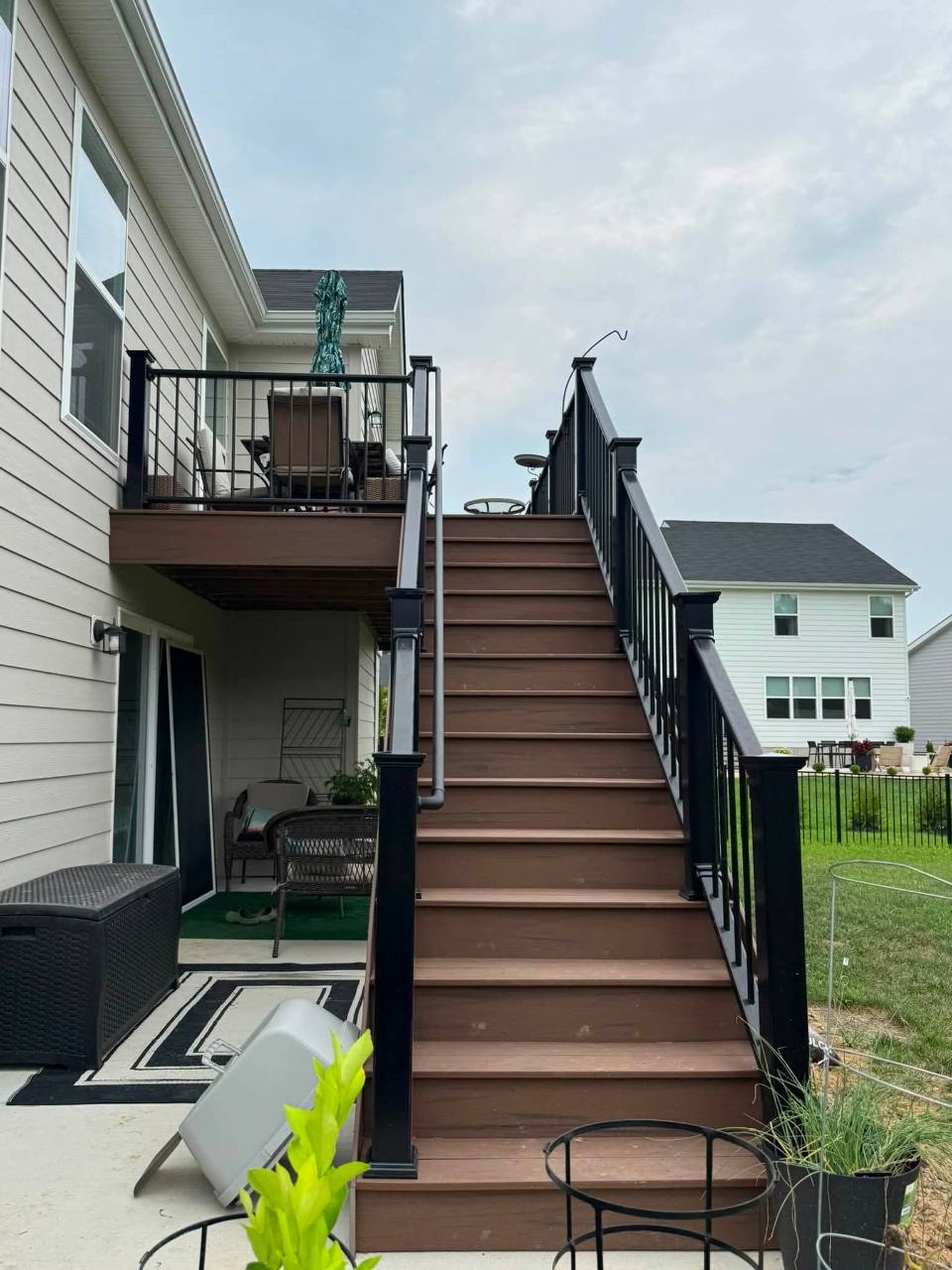 Brown Oak stairs and black railing viewed from the patio