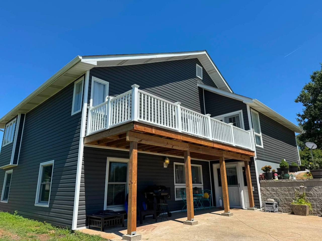 Gray composite elevated deck with white railing at a dark-sided home