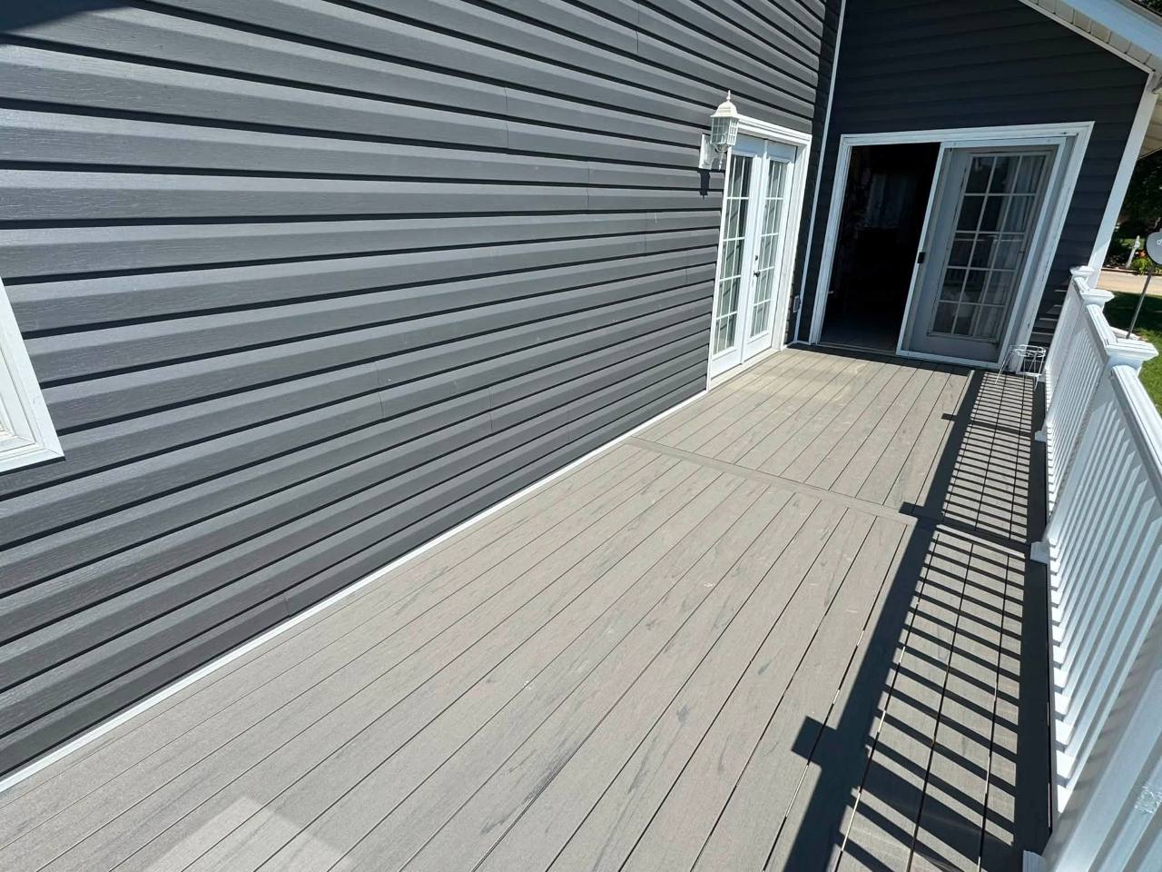 Gray composite deck surface beside dark siding